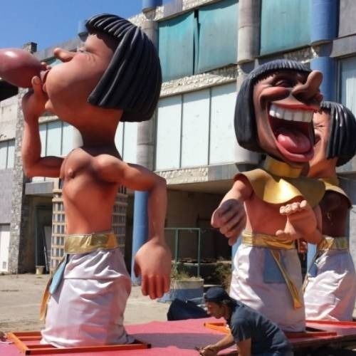 Large statues in ancient Egyptian attire with exaggerated facial expressions on display at an outdoor event.