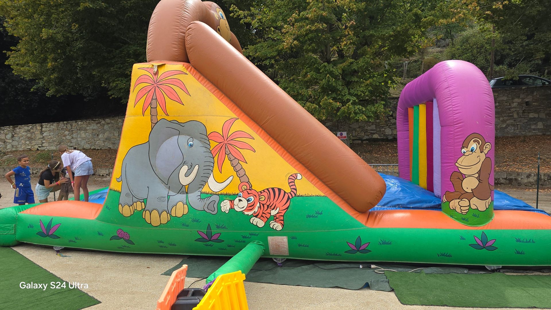 Colorful inflatable playground for children with cartoon characters of an elephant, tiger, and monkey.