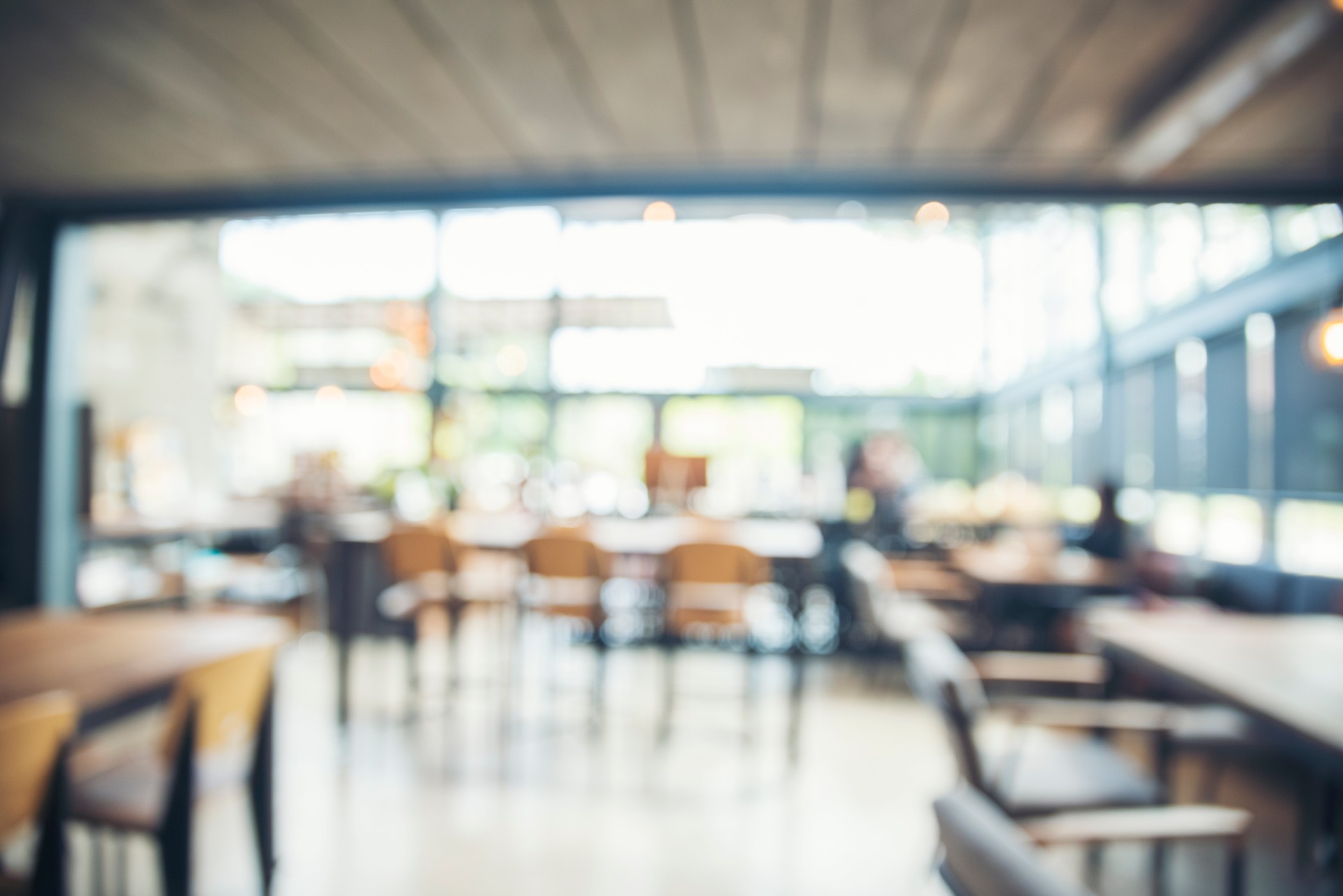 Blurred background cafe coffee shop restaurant in shopping mall with light bokeh business event retail store. Blurry background interior design bar table chair windows decorate indoor space display